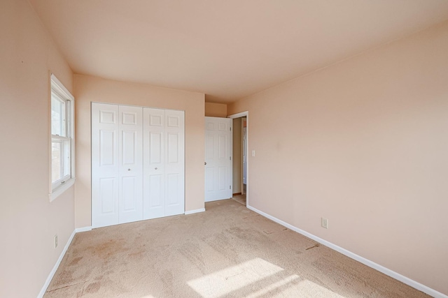 unfurnished bedroom featuring light colored carpet and a closet