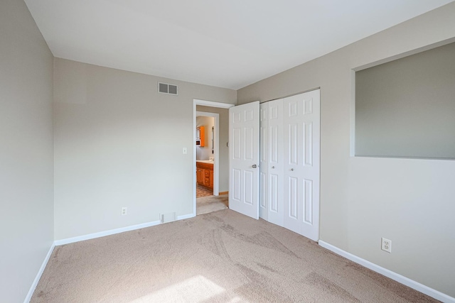 unfurnished bedroom featuring light colored carpet and a closet