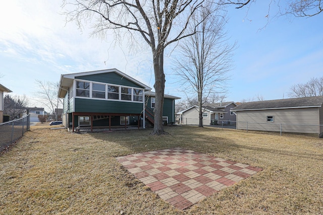 back of property with a sunroom, a lawn, and a patio area