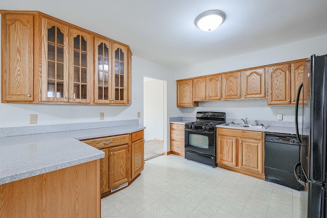 kitchen featuring light stone counters, sink, tasteful backsplash, and black appliances