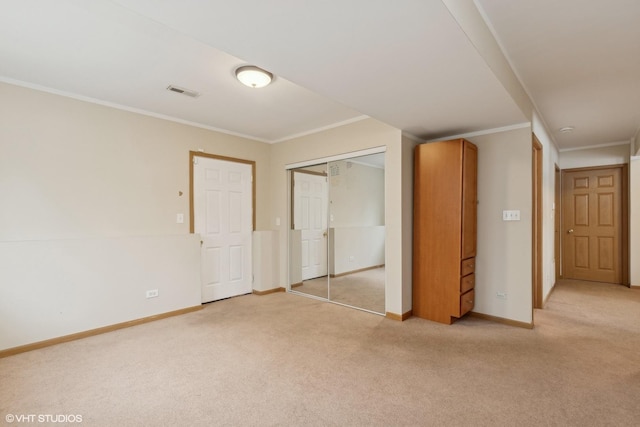 unfurnished bedroom featuring crown molding, light carpet, and a closet