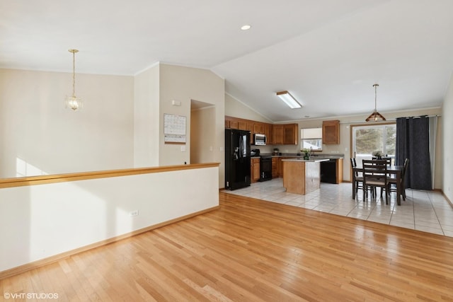 kitchen featuring pendant lighting, a center island, light hardwood / wood-style flooring, and black appliances