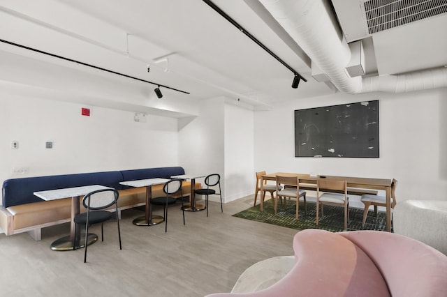 dining space with rail lighting and light hardwood / wood-style flooring