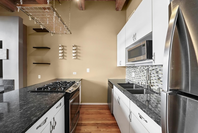 kitchen featuring sink, light hardwood / wood-style flooring, white cabinetry, stainless steel appliances, and tasteful backsplash