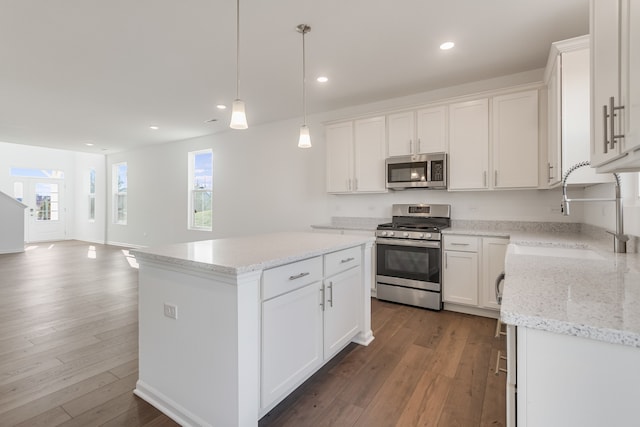 kitchen featuring pendant lighting, sink, white cabinets, a center island, and stainless steel appliances