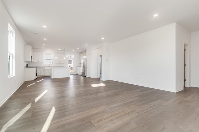 unfurnished living room featuring wood-type flooring and sink