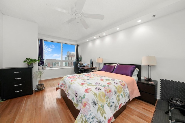 bedroom featuring a city view, recessed lighting, a ceiling fan, baseboards, and light wood-style floors