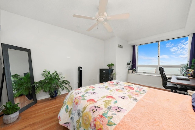 bedroom with a ceiling fan, baseboards, visible vents, and wood finished floors