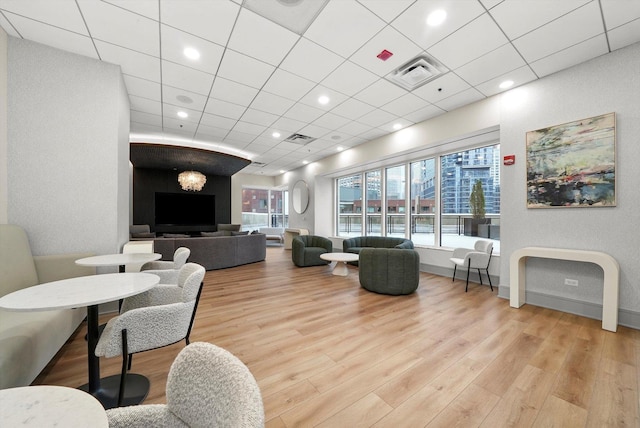 living area featuring a drop ceiling, wood finished floors, and visible vents