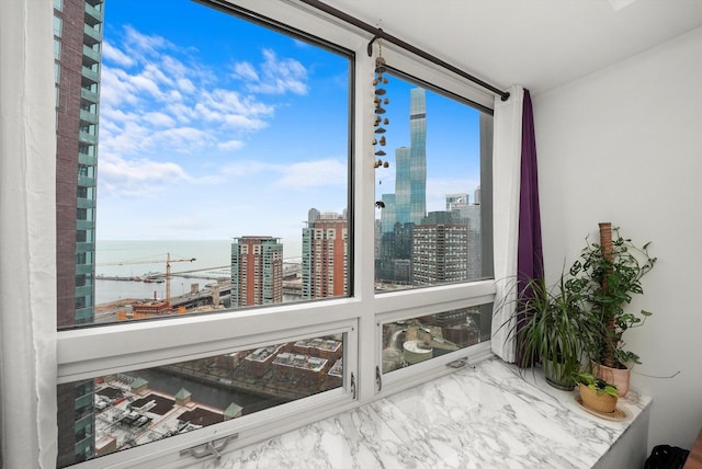 sunroom featuring a wealth of natural light, a city view, and a water view