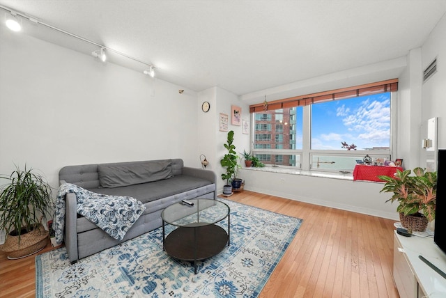 living area with hardwood / wood-style flooring, baseboards, visible vents, and rail lighting