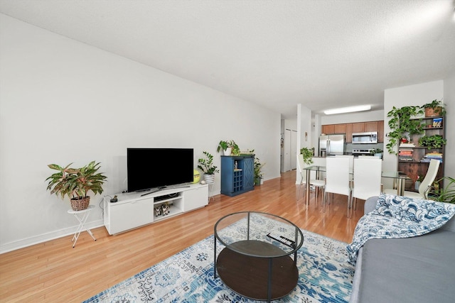 living room featuring light wood-style flooring, baseboards, and a textured ceiling