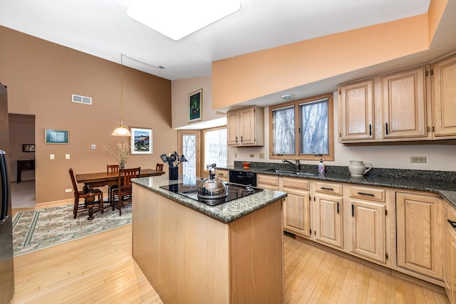 kitchen featuring light brown cabinetry, black appliances, and a center island