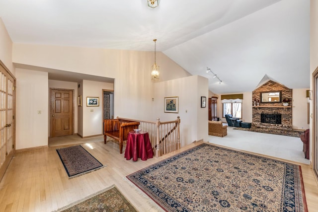 foyer entrance featuring an inviting chandelier, lofted ceiling, a fireplace, and light hardwood / wood-style flooring