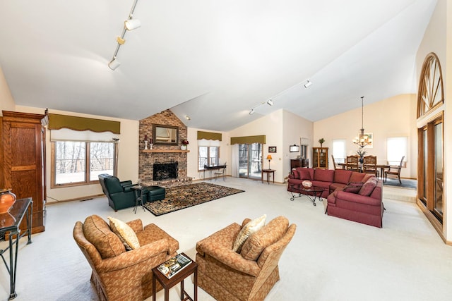 carpeted living room with an inviting chandelier, a brick fireplace, vaulted ceiling, and rail lighting