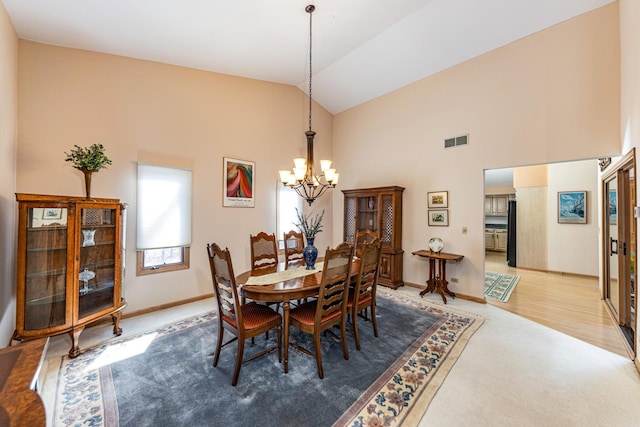 dining room with an inviting chandelier, high vaulted ceiling, and hardwood / wood-style floors