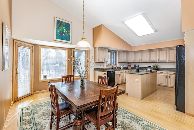 dining area with high vaulted ceiling and light hardwood / wood-style flooring