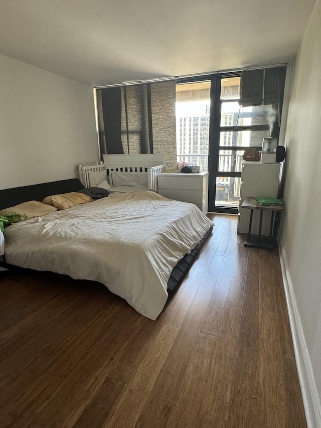 bedroom featuring a wall of windows and dark hardwood / wood-style floors