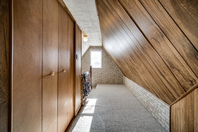 additional living space featuring light carpet, wooden walls, lofted ceiling, and brick wall