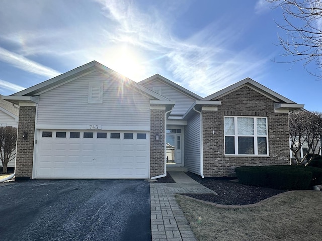 single story home with a garage, driveway, and brick siding