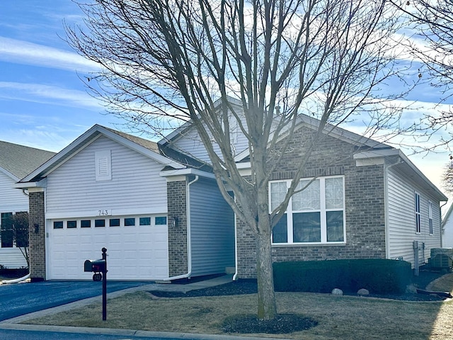 view of front facade featuring driveway, brick siding, an attached garage, and a front yard