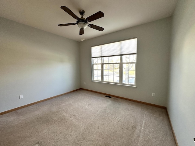 carpeted spare room featuring visible vents, baseboards, and ceiling fan