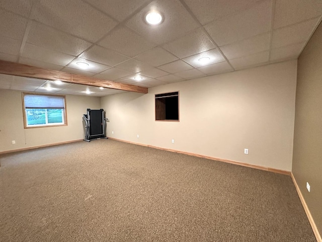 basement with carpet floors, a drop ceiling, and baseboards