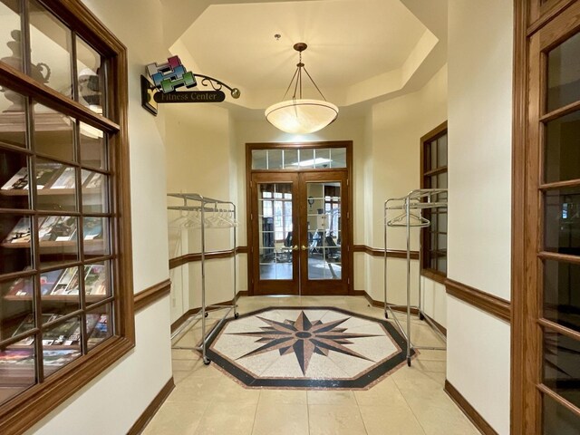 entrance foyer featuring light tile patterned flooring, baseboards, a raised ceiling, and french doors