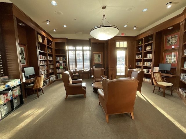 sitting room with built in features, bookshelves, and carpet flooring