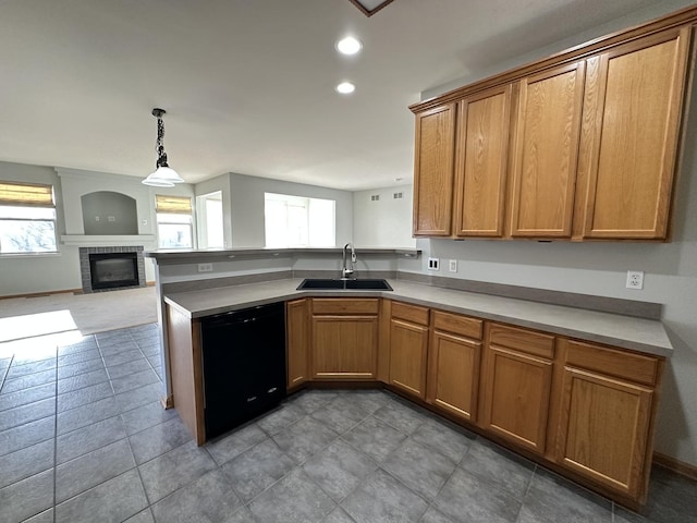 kitchen with black dishwasher, brown cabinets, open floor plan, light countertops, and a sink