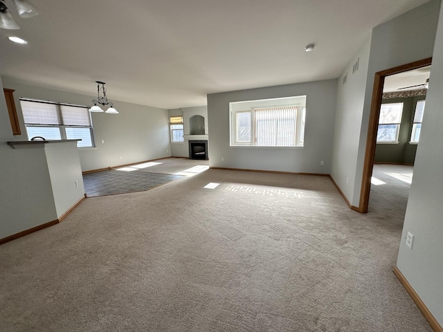 unfurnished living room with light carpet, visible vents, and baseboards