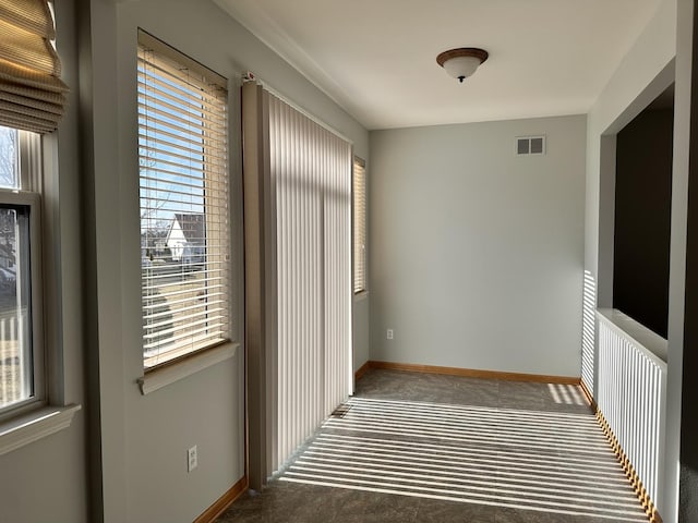 hall with plenty of natural light, visible vents, and baseboards