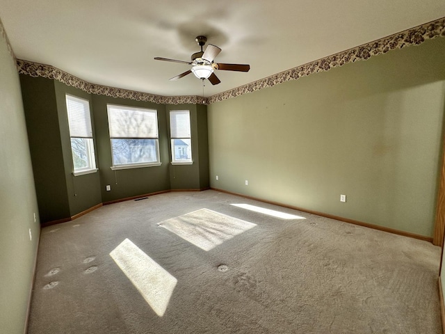 unfurnished room with carpet floors, a ceiling fan, and baseboards