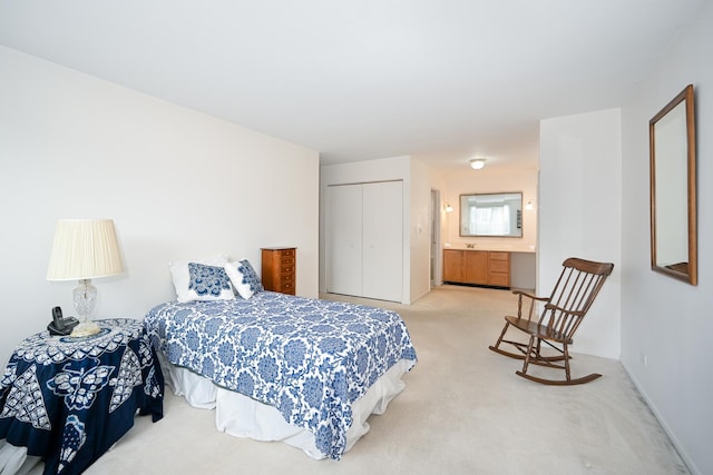 bedroom featuring ensuite bathroom, a closet, baseboards, and light colored carpet