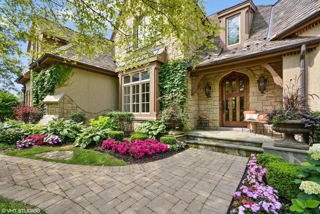 view of exterior entry featuring stone siding, french doors, and stucco siding