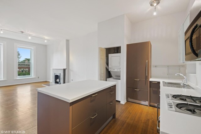 kitchen featuring stacked washing maching and dryer, stainless steel microwave, light countertops, and a center island