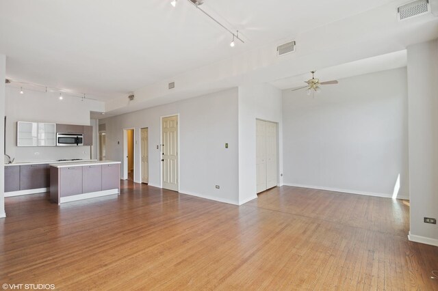 unfurnished living room featuring baseboards, a ceiling fan, visible vents, and light wood-style floors