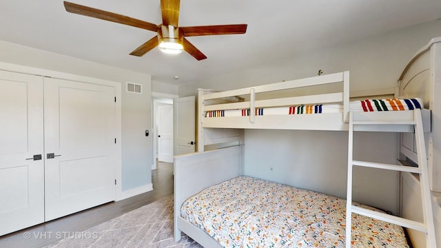 bedroom with a closet, visible vents, ceiling fan, wood finished floors, and baseboards