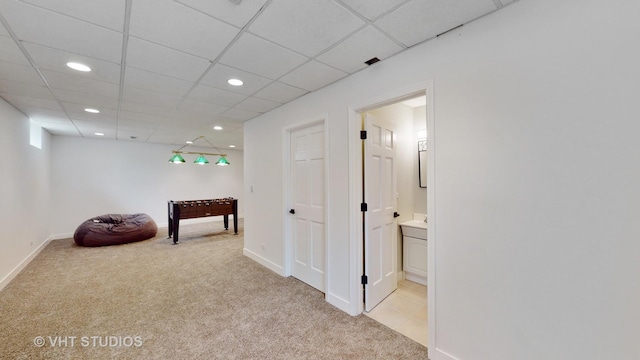 hall featuring recessed lighting, light colored carpet, a drop ceiling, and baseboards