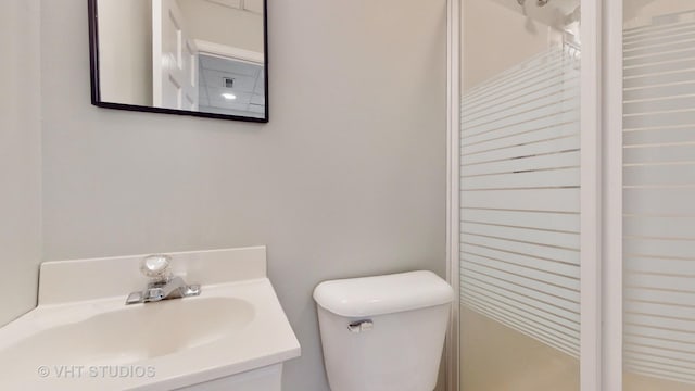 bathroom with walk in shower, vanity, and toilet