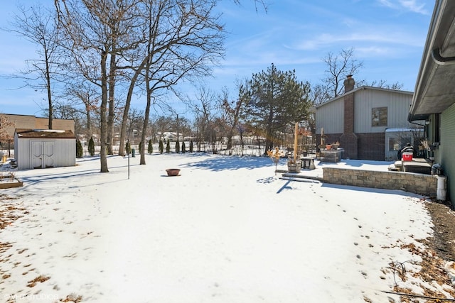 snowy yard featuring a storage unit and an outdoor structure