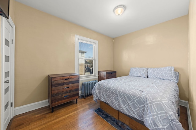 bedroom with radiator heating unit, wood finished floors, and baseboards