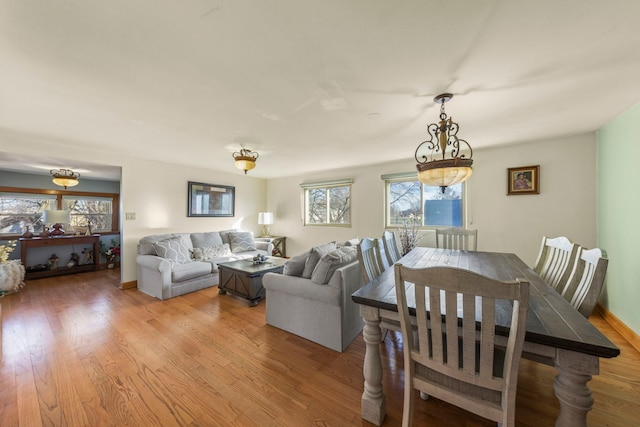 dining space with light wood-style floors, plenty of natural light, and baseboards