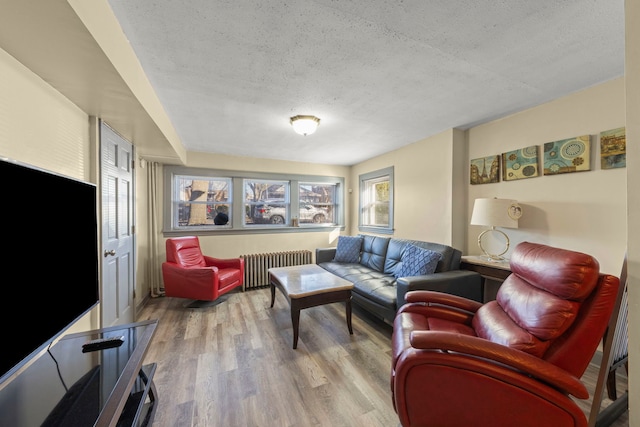 living area featuring radiator heating unit, a textured ceiling, and wood finished floors