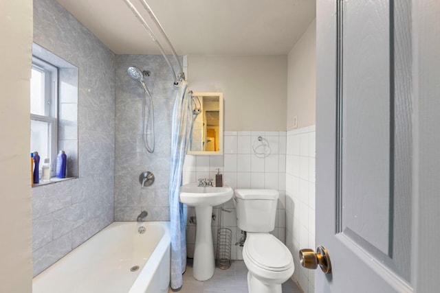 bathroom featuring a wainscoted wall, tile walls, shower / bathtub combination, toilet, and tile patterned floors