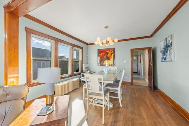 dining area with crown molding, radiator, wood finished floors, a chandelier, and baseboards