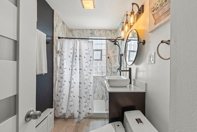 full bathroom with a textured wall, wood finished floors, a shower stall, and vanity