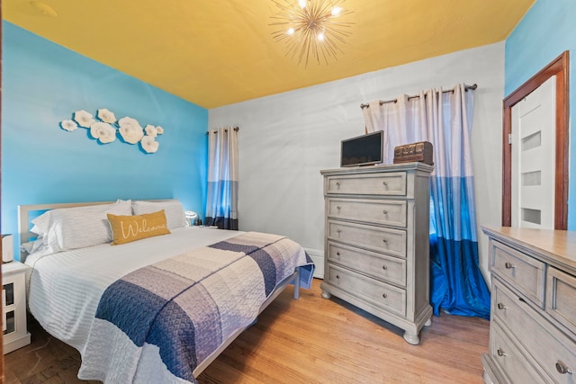 bedroom featuring light wood-type flooring and a notable chandelier