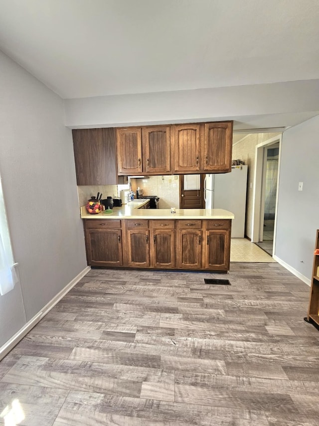 319 S Reed St, Joliet, IL 60436 - kitchen featuring freestanding refrigerator, light wood-style flooring, light countertops, baseboards, and a peninsula