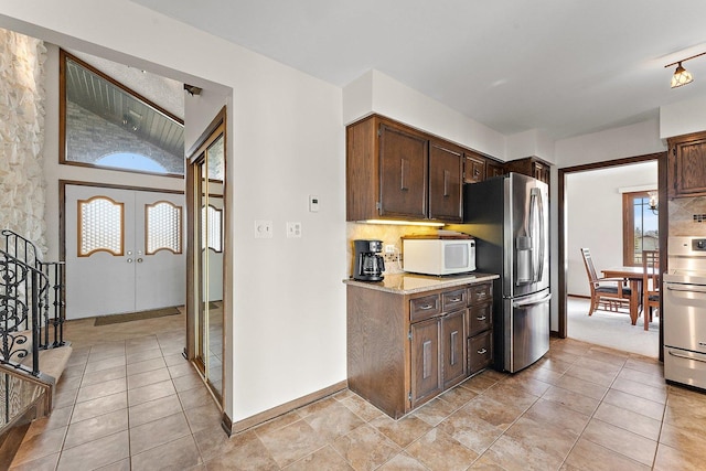 kitchen with french doors, dark brown cabinetry, stainless steel fridge with ice dispenser, and tasteful backsplash